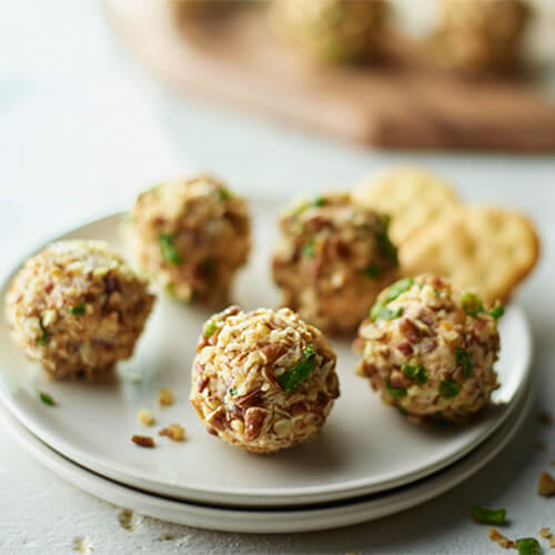 Turkey bacon cheese balls on a grey plate sitting on a white wood table.