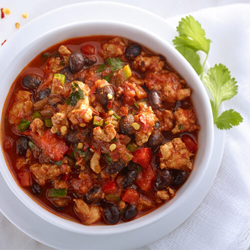 Some great looking turkey chili and black beans in a white bowl.