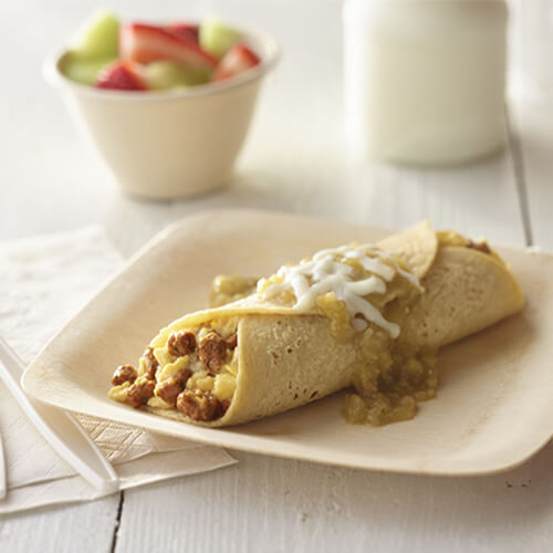 Single breakfast enchilada stuffed with eggs, JENNIE-O® Turkey Chorizo and topped with salsa on a white plate next to a bowl of mixed fruit.