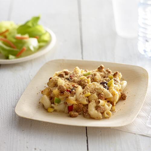 Elbow macaroni and cheese mixed with JENNIE-O® Turkey Chorizo on a white plate next to a side salad.