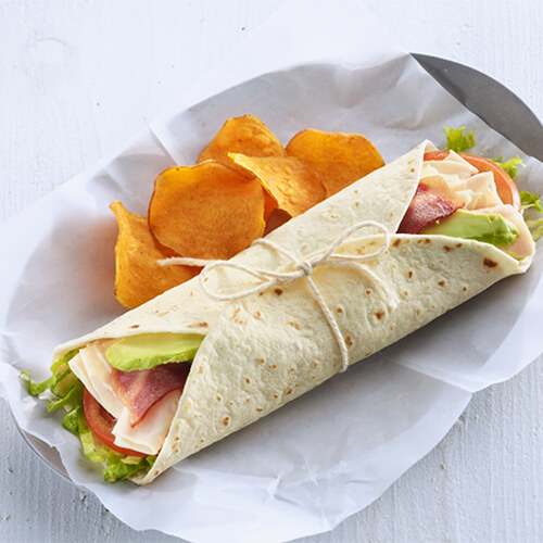 Turkey club wrap with a side of chips on a grey plate.