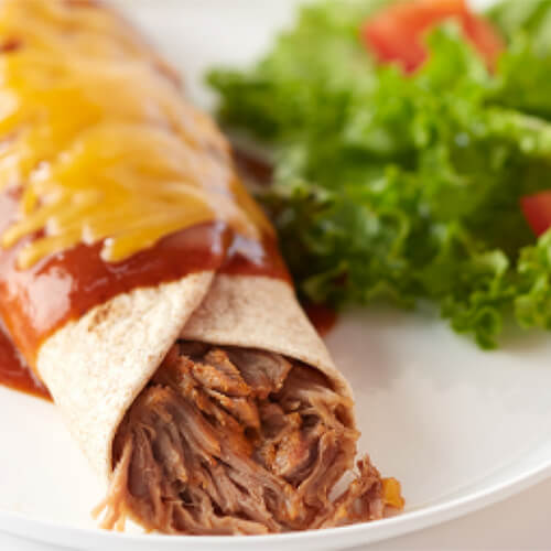 Slow-roasted dark turkey stuffed in a tortilla and topped with enchilada sauce and cheese, served on a white plate with a side salad.