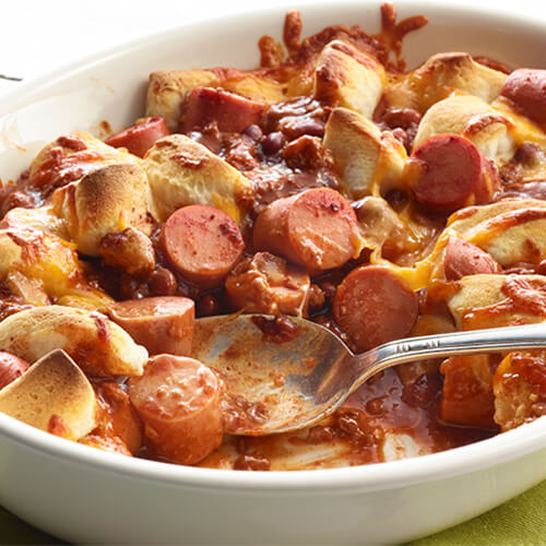 Turkey frank casserole, topped with cheese in a white bowl.