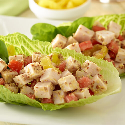 Easy lettuce wraps made with fresh veggies, roast turkey breast and whole grain mustard, served on a white plate.