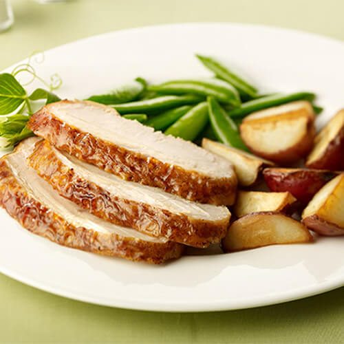 A generous portion of roast turkey, potatoes, and tender peas, on a white plate.