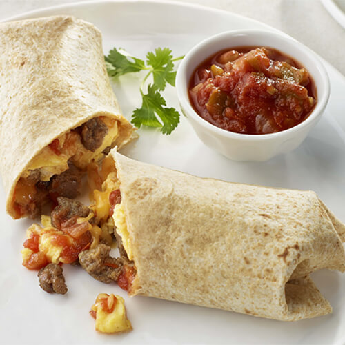 A hearty breakfast burrito filled with turkey sausage, scrambled eggs, salsa, and melted cheese, served on a white plate with a side of salsa.