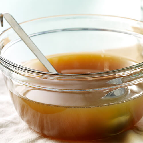A savory portion of turkey stock served in a glass bowl atop a white cloth.