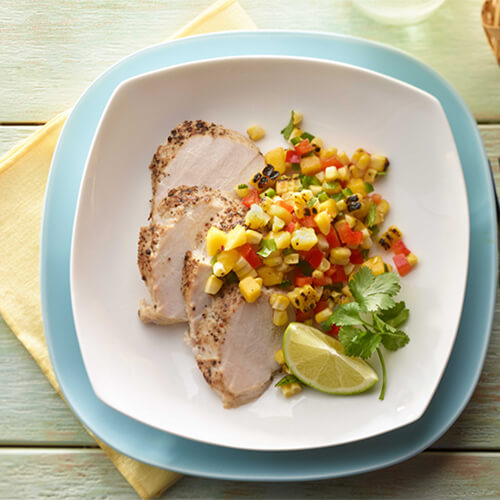 Turkey tenderloin with grilled corn mango salsa stacked on blue and white plates.