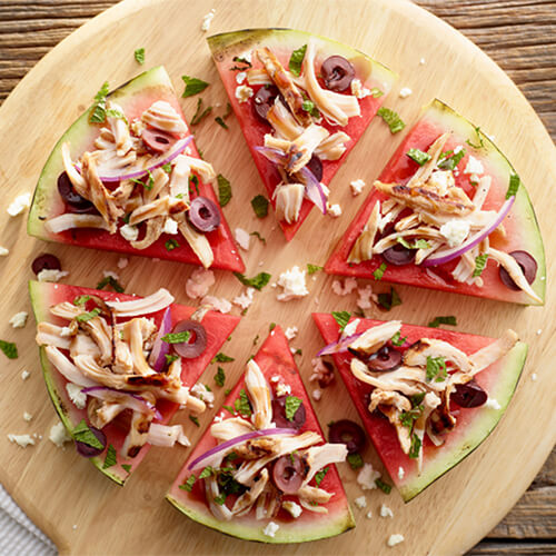 Watermelon feta turkey pizza garnished with basil on a wood plate.