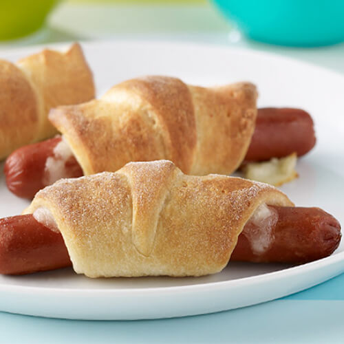 Three turkey franks wrapped in crescent rolls and stuffed with cheese.