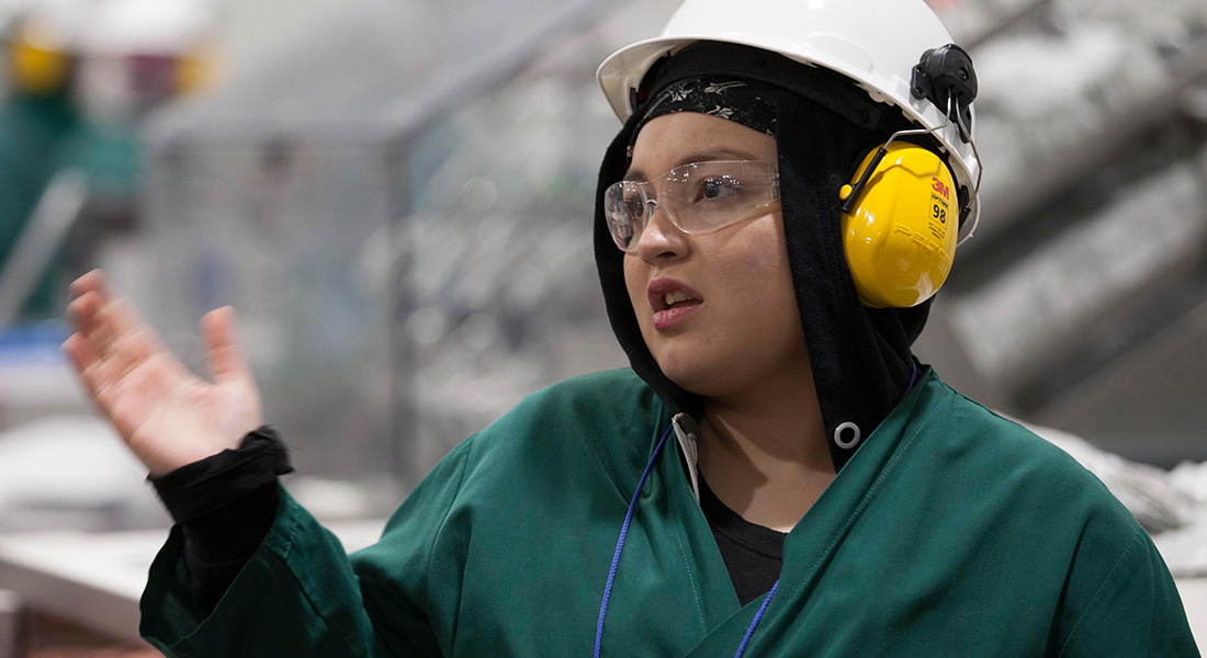 A JENNIE-O® factory worker in full protective gear going about her work day.